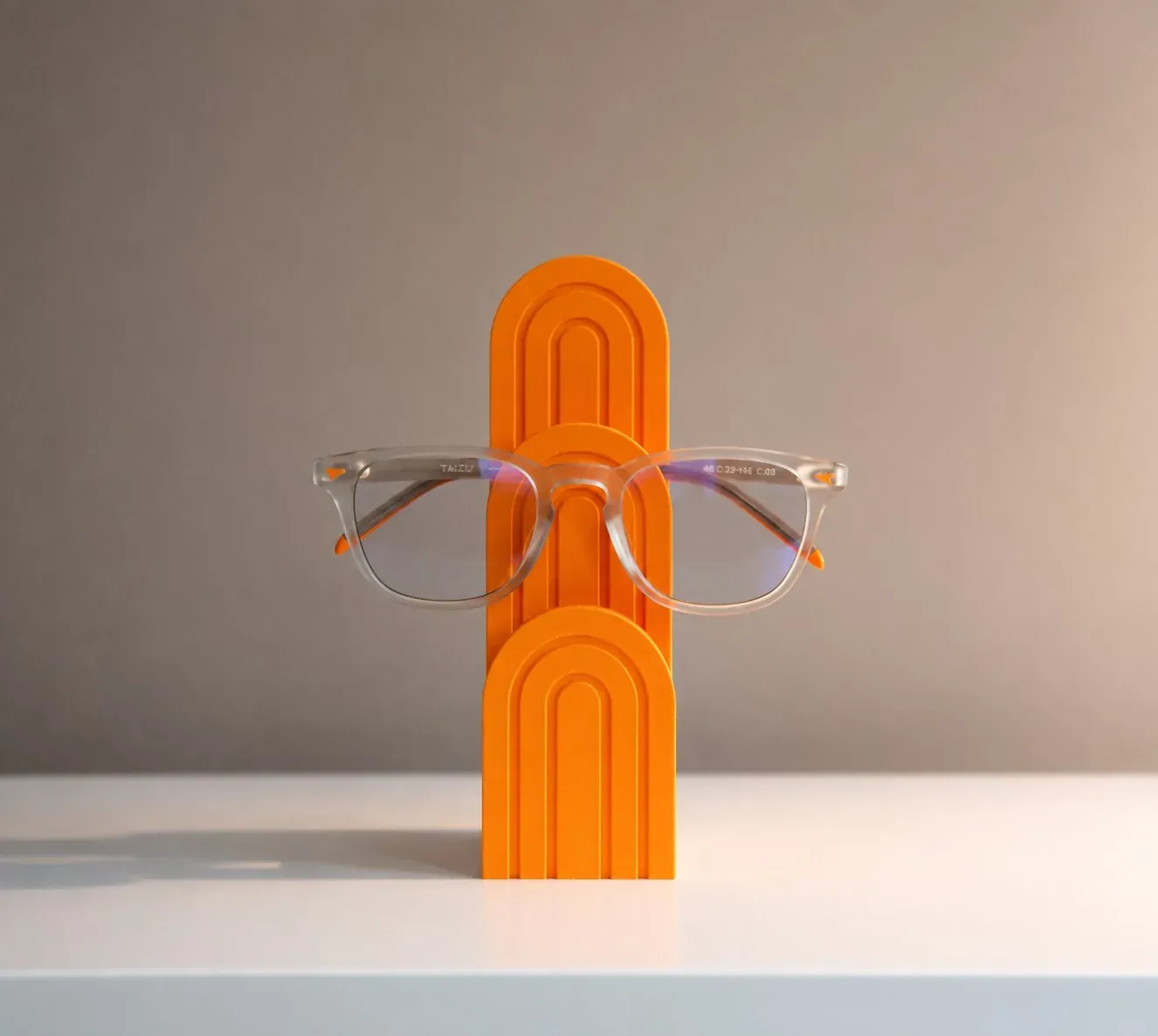 Gafas transparentes colgadas del Arco para Gafas naranja, en una escena de escritorio