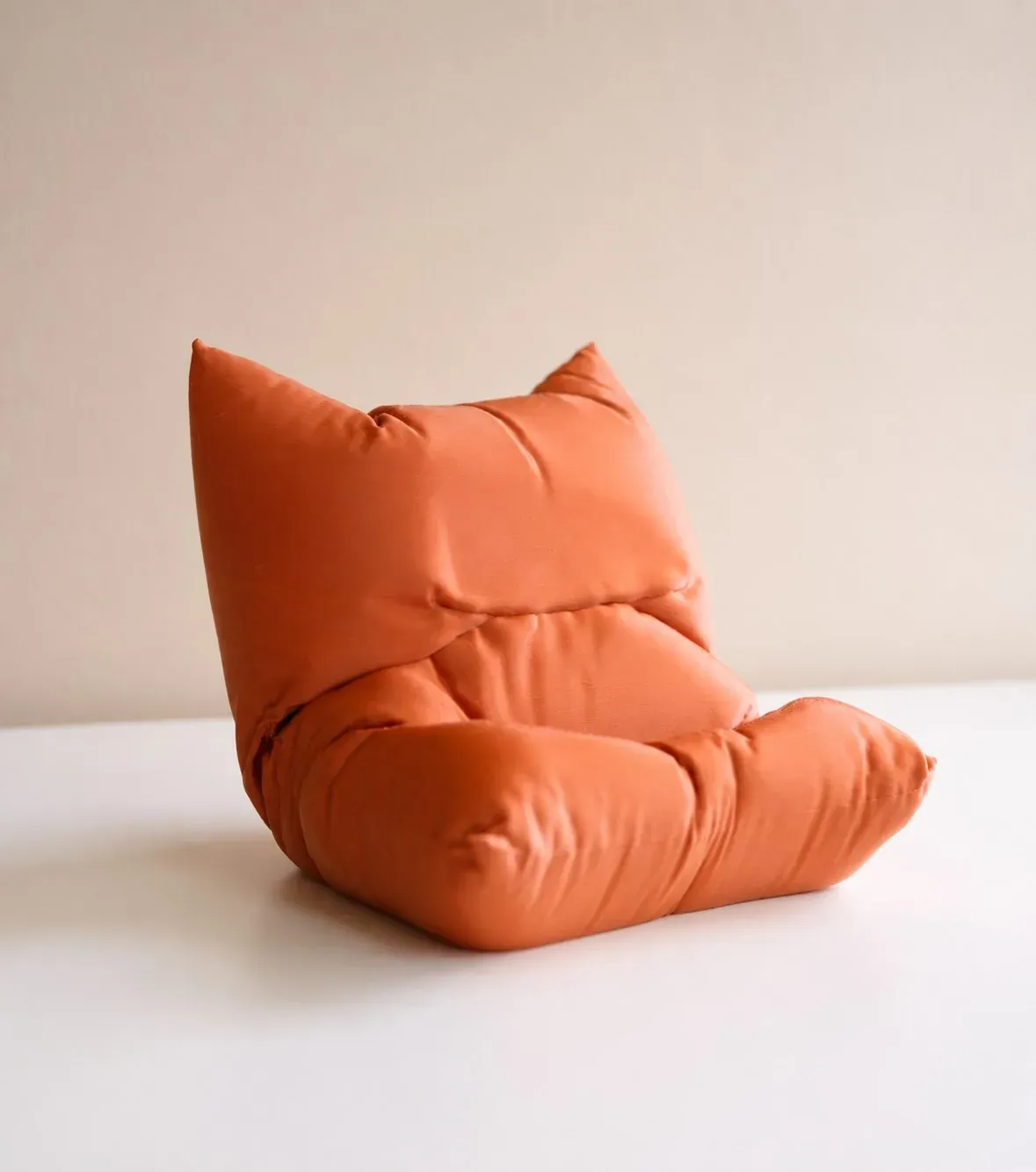 Soporte con forma de cojín impreso en 3D en naranja, visto de lado y vacío
