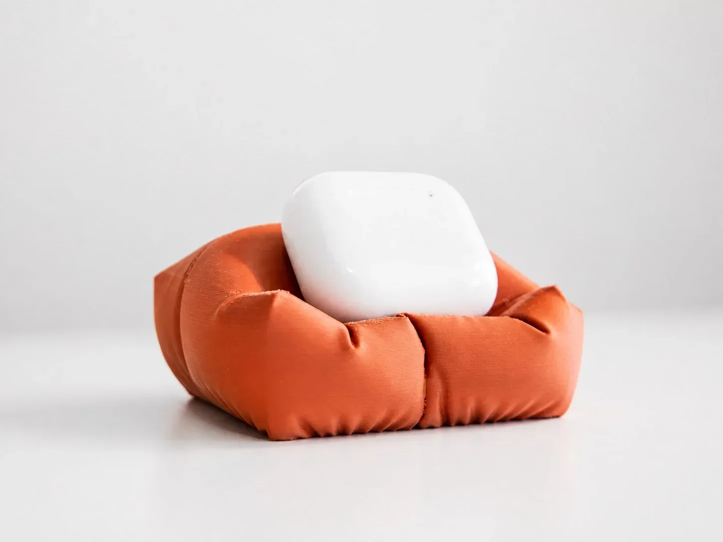 Estuche blanco de audífonos dentro de la cama cojín naranja