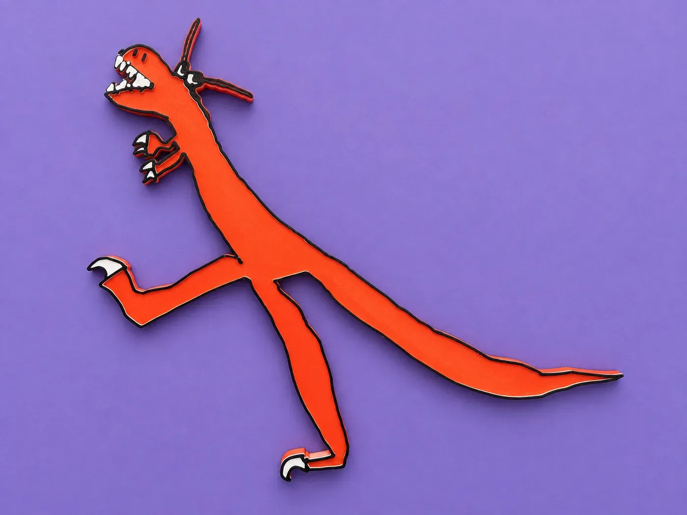 El dragón de Juan Tomás convertido en juguete: naranja con contorno negro y dientes blancos