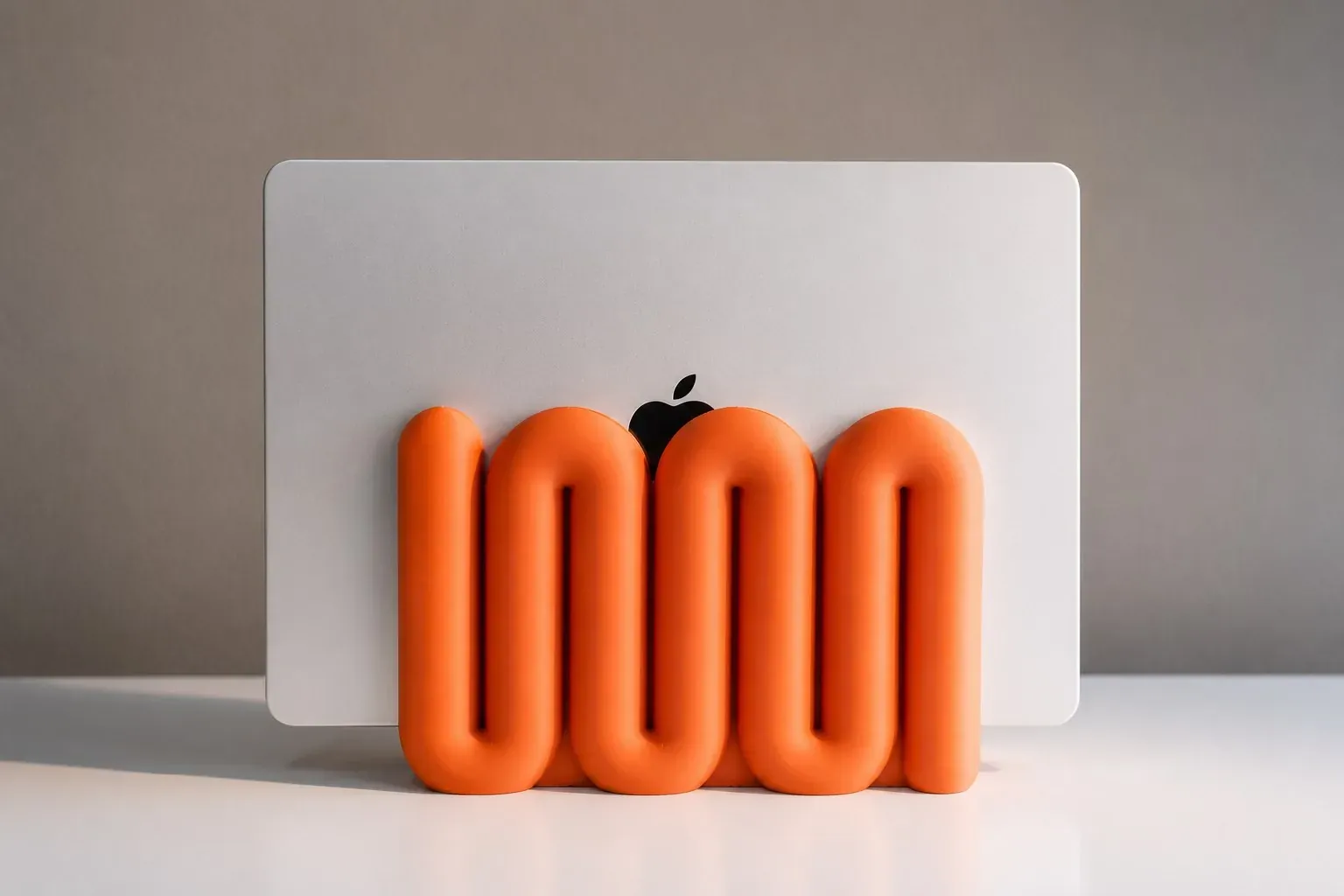 Soporte Onda naranja con un portátil plateado apoyado, en luz suave