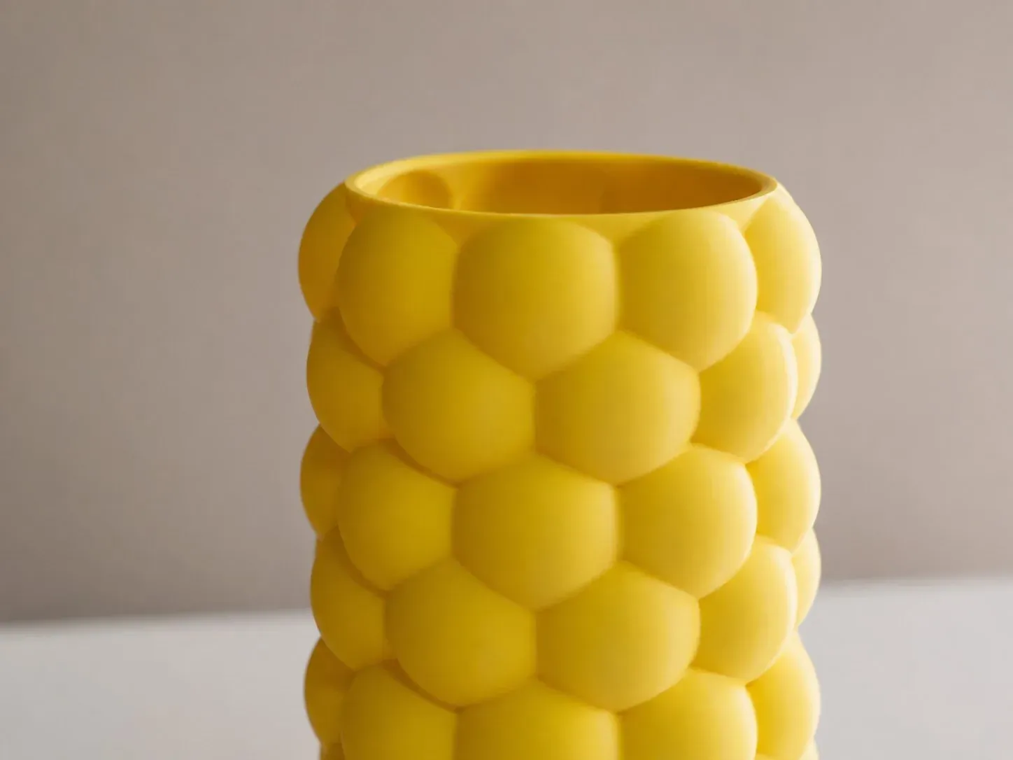 Florero Colmena amarillo sobre fondo neutro, en luz suave