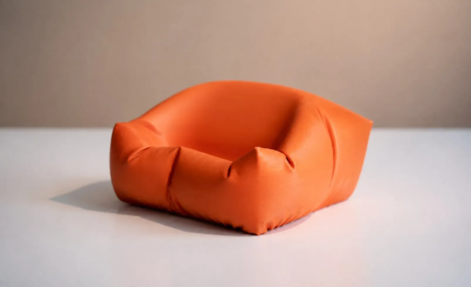 Cama cojín naranja vista en ángulo, con las paredes fruncidas a la vista