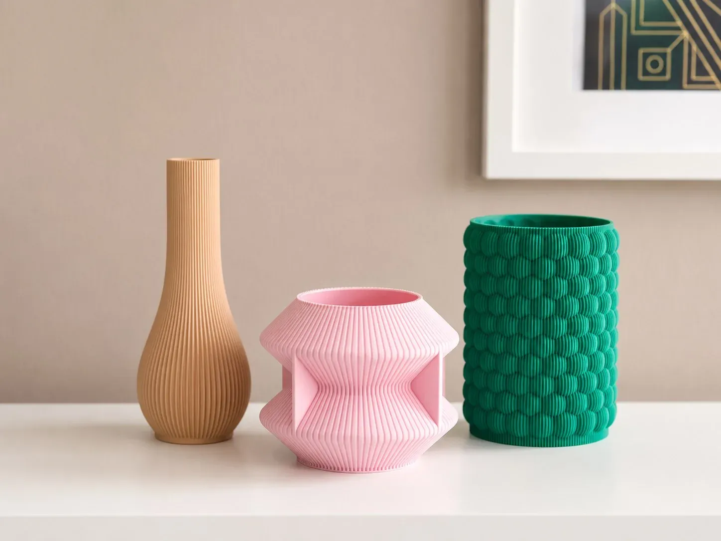 Florero Gota beige, Florero Reloj rosado y Florero Burbujas verde alineados en una repisa